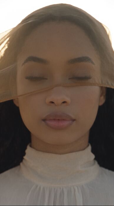 Eyes closed beneath a sheer veil