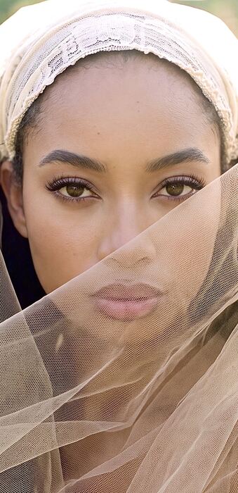 Orie King behind a sheer veil, looking toward the camera